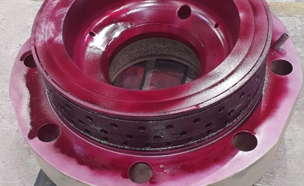 KIMI technician performing dimensional and NDT inspection on reconditioned 2-stroke cylinder cover.